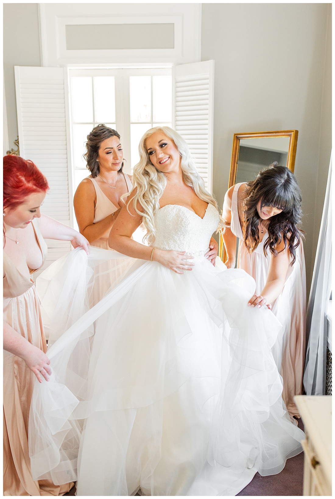bridesmaids helping bride get in dress