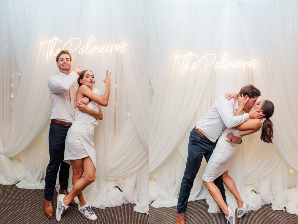 Bride and groom kissing in front of neon sign with their last name