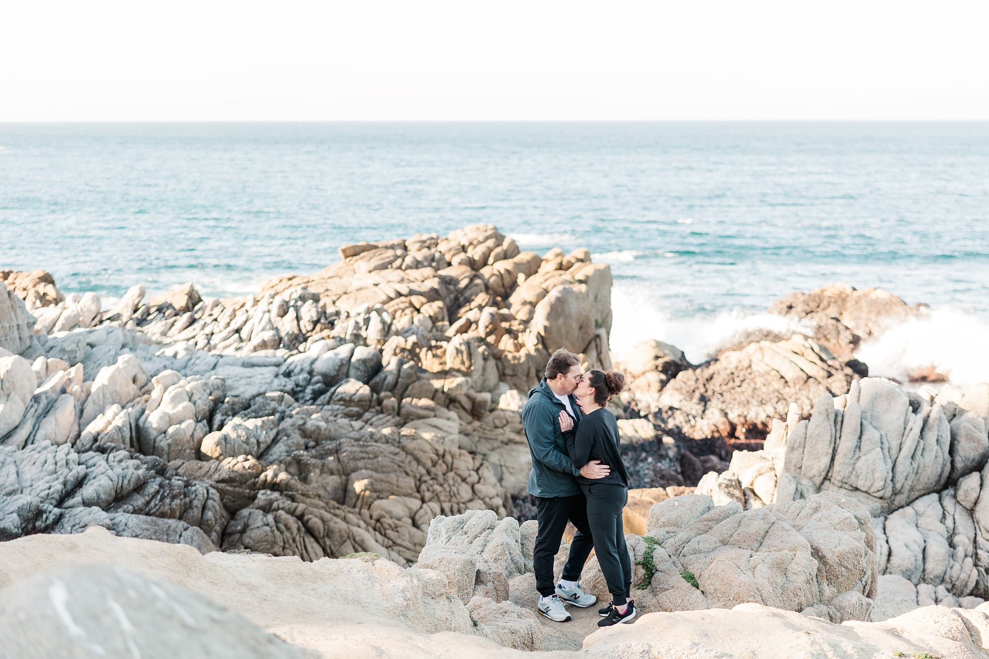 couple kissing on the rocks by the beach