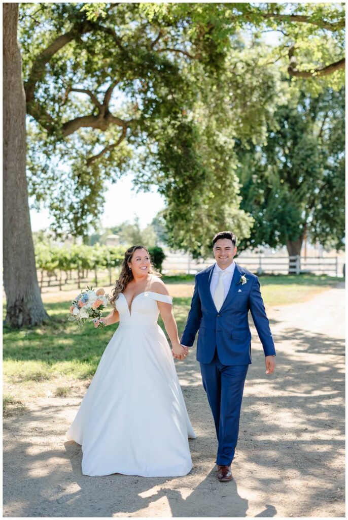 Bride and groom walking together through vineyard at Garre winery wedding | Livermore wedding photographer candid moment
